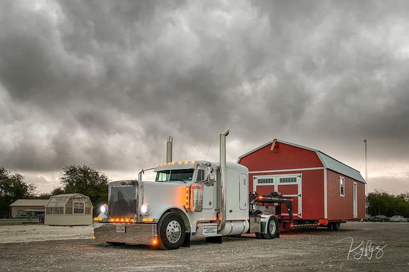 Semi-truck loaded with a big storage shed